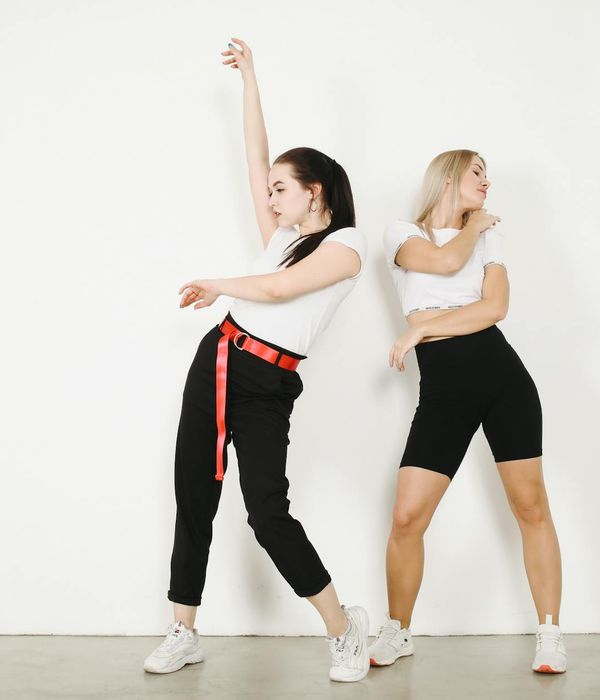 Woman in a dynamic yet graceful movement pose against a mint background.